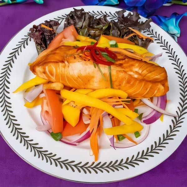 Grilled salmon fillet with mango, red onion, and bell pepper salad on a white plate.